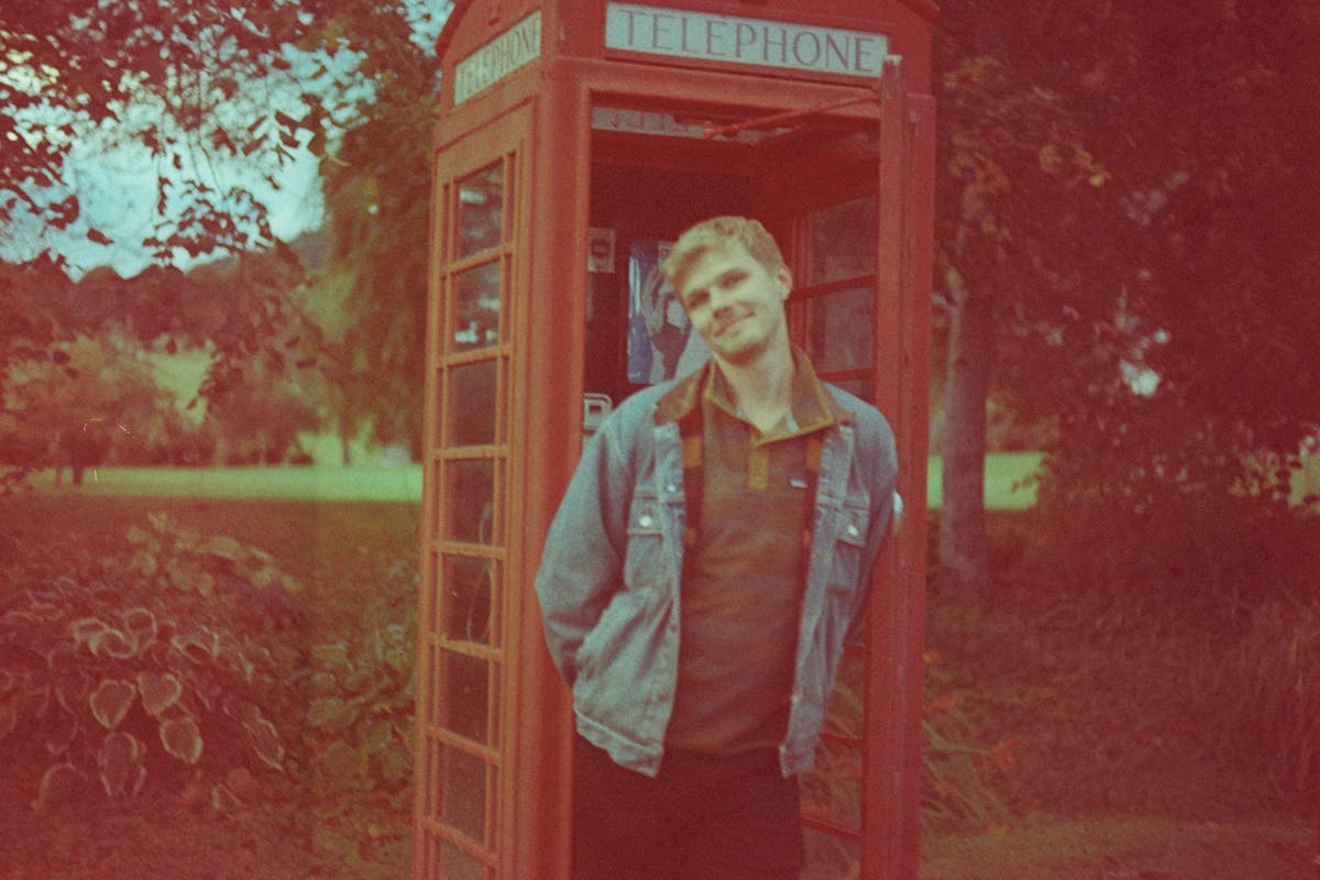 Allister standing in a red phone booth