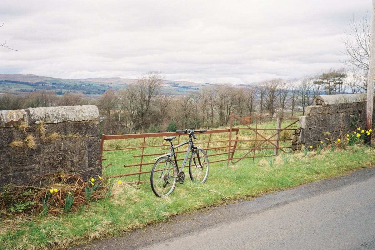 A bicycle leaned against a gate in the countryside