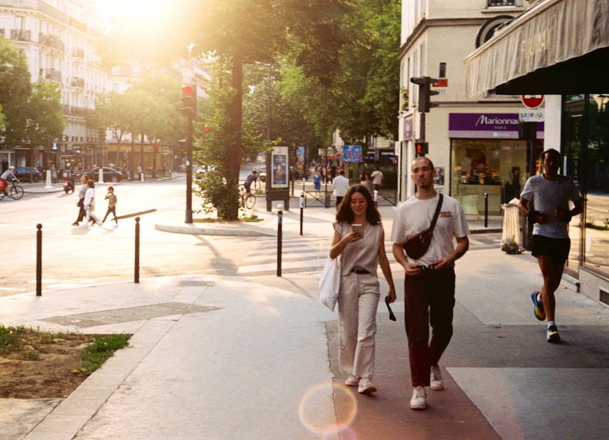 People walking on a paris sidewalk at dusk