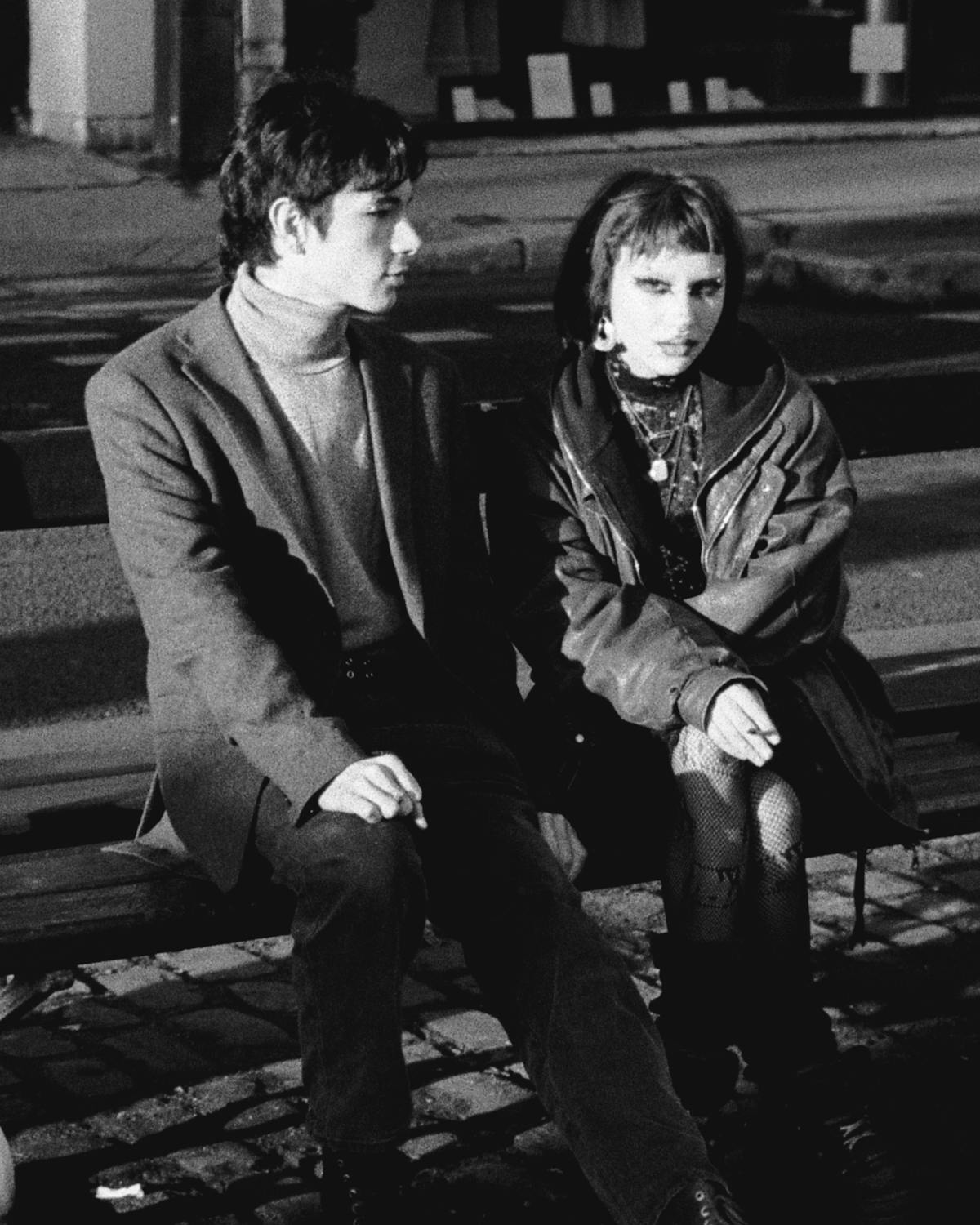 A young couple sitting on a bench.