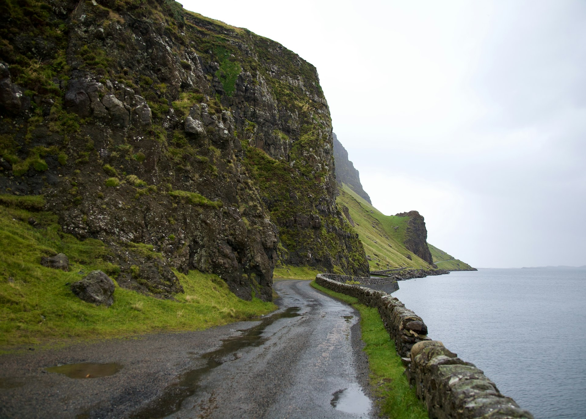 A rugged road running between the ocean shore and rocky cliffs