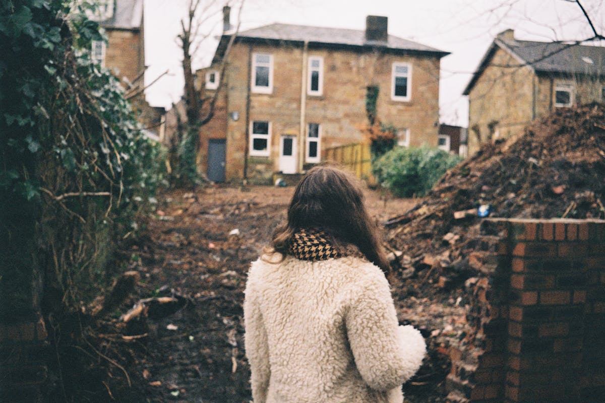 A woman standing in front of an empty yard