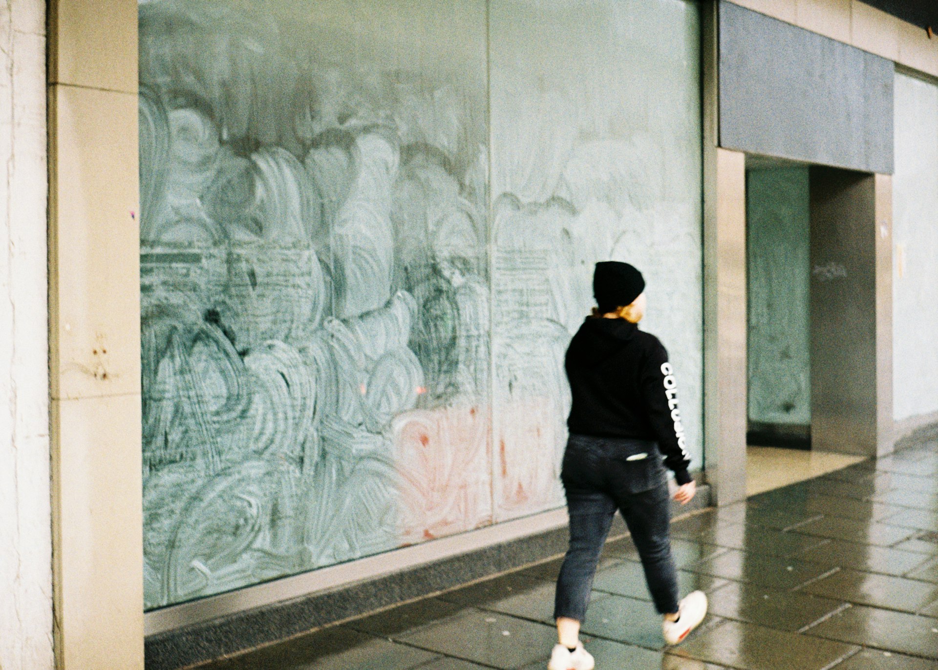 A woman walking past an empty storefront