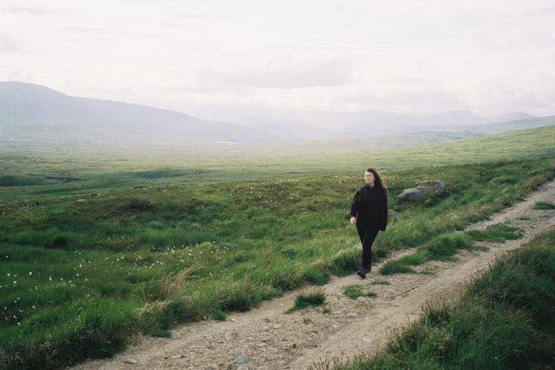 Claire walking on the hillside, with an empty moor and mountains in the background