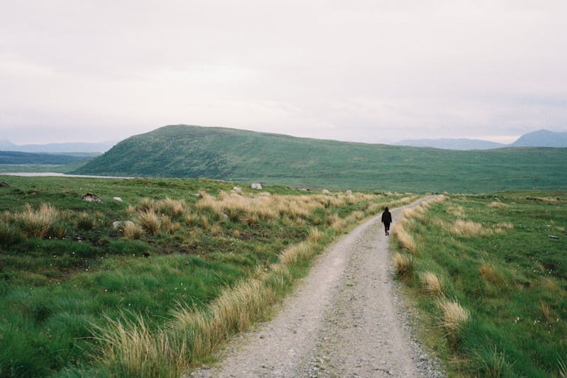 A photo of Claire walking downhill towards a lush glen