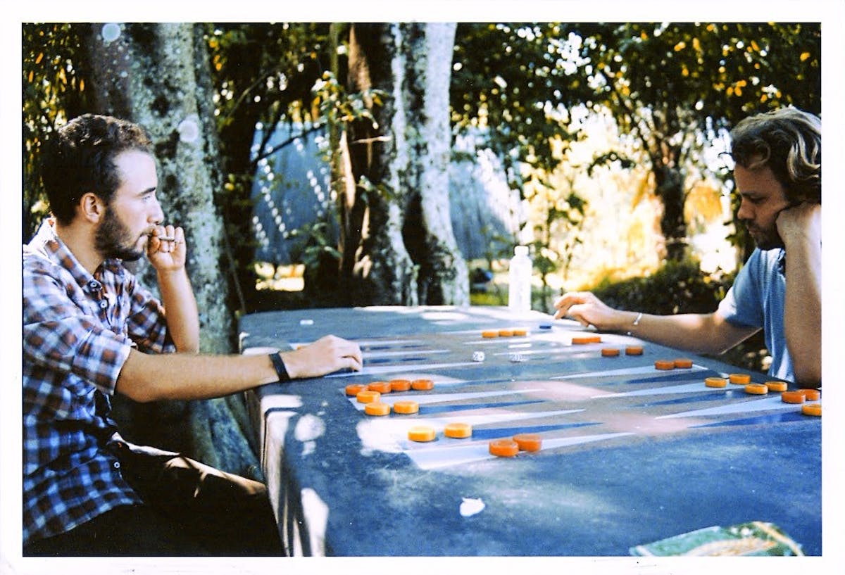 Two guys playing backgammon in the tropics